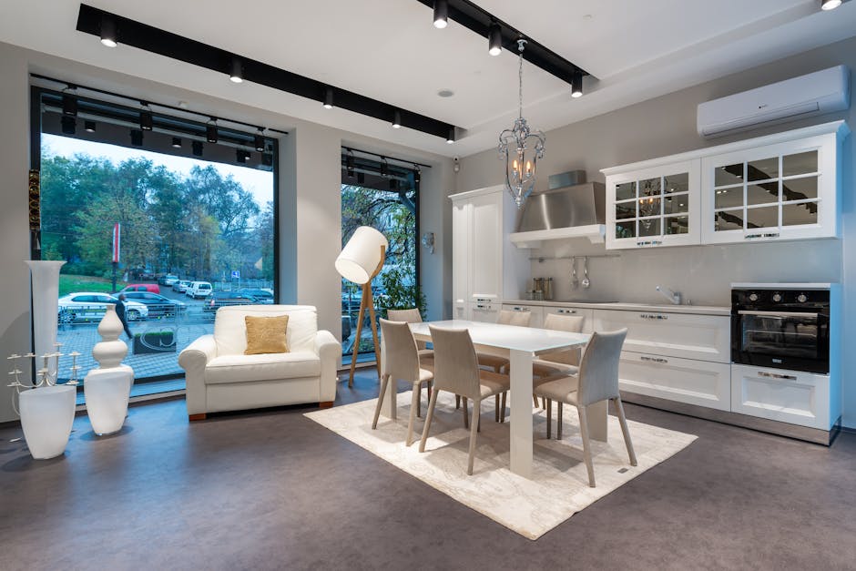 Comfortable armchair and dining table with chairs placed in spacious kitchen with classic styled white cupboards and modern appliances