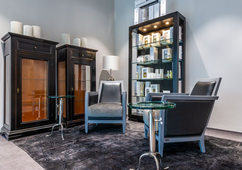 Various decorative elements laced on classic styled wooden cupboard and shelves near leather armchairs in stylish apartment