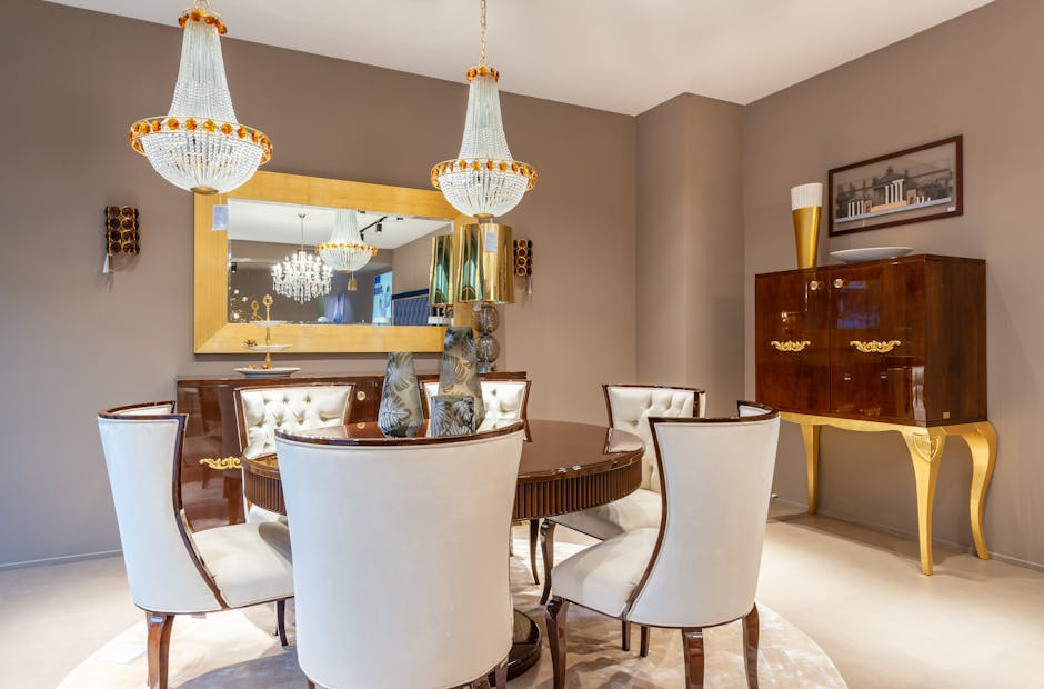 Chairs at table with decorative vases under glowing chandeliers placed near wall with and mirror and vintage styled cabinet in apartment